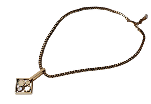 Collana décolleté con catena quadrata color oro antico e pendente con motivi astratti.